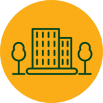 Rundes Icon für "Klinikeigene Betriebswohnungen" mit dunkelgrünem Element bestehend aus einem Wohngebäude mit zwei Bäumen rechts und links daneben, auf einem orangenen Hintergrund.