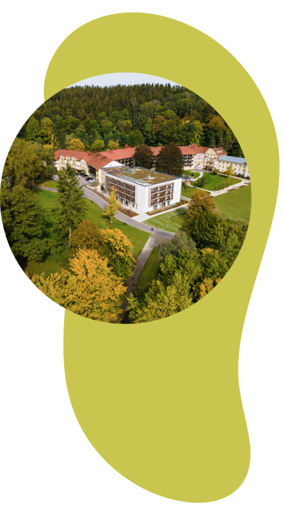 Luftbild der Klinik Wartenberg in einem kreisrunden Rahmen. Im Hintergrund ein helsgrünes, längliches Designelement.