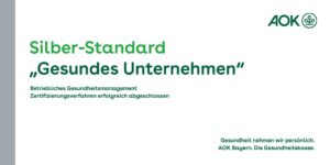 Siegel der AOK für Silber-Standard "Gesundes Unternehmen" Betriebliches Gesundheitsmanagement; Zertifizierungsverfahren erfolgreich abgeschlossen. In grüner Schrift auf weißem Hintergrund.